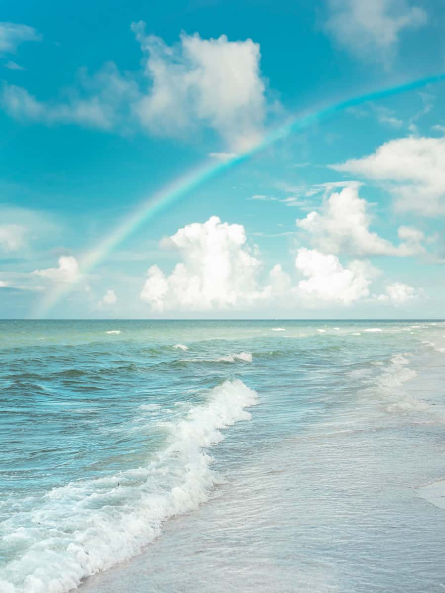 Sanibel Island's magic revealed: A radiant rainbow graces the beach, merging sky and sea.