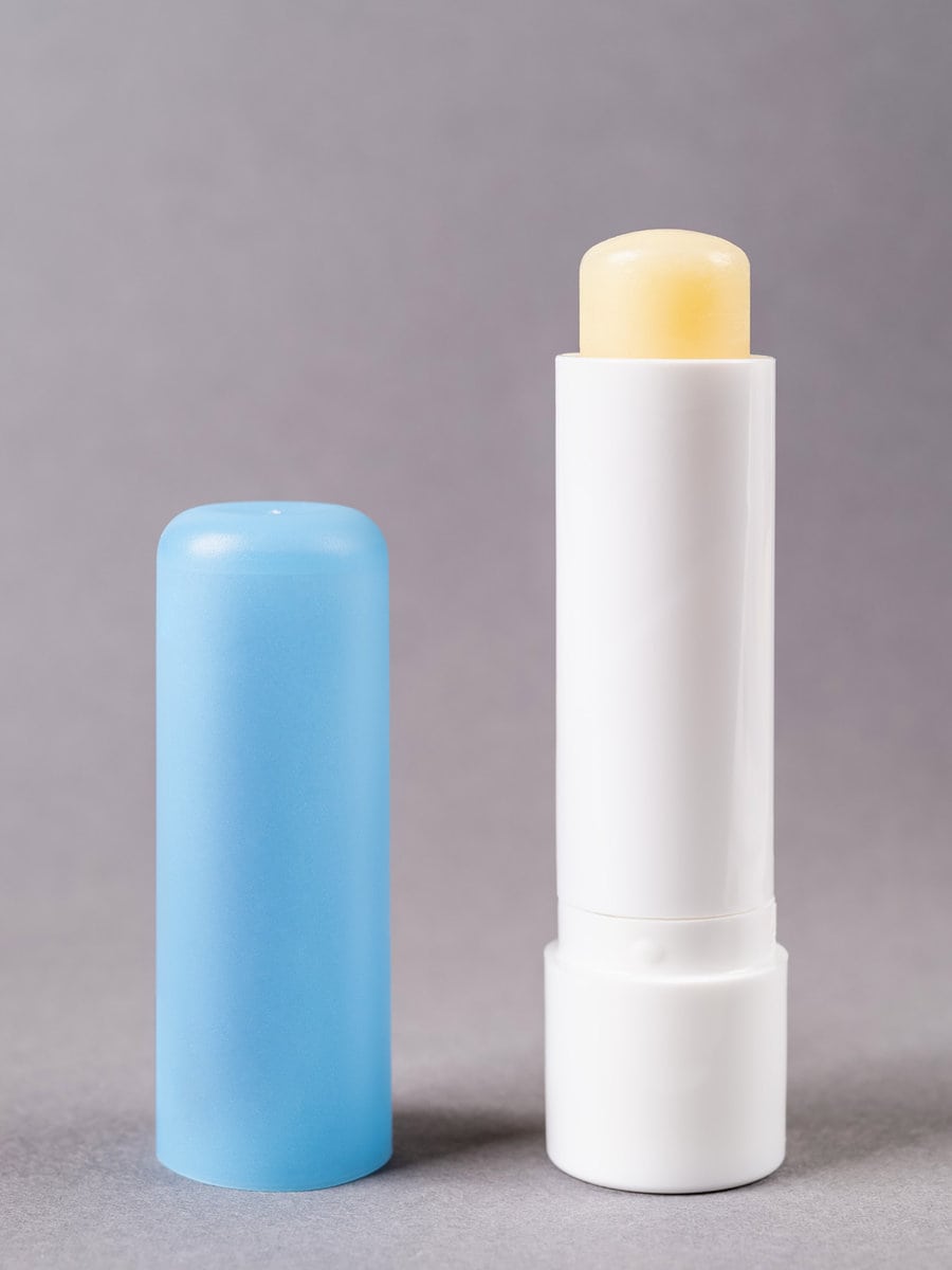 Сhapstick open tube over gray background. Moisturizing lip balm for dry lips macro. 