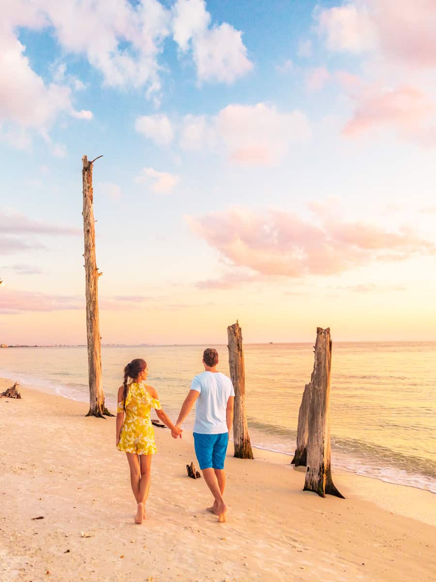 Couple walking on beach at sunset romantic travel getaway, idyllic Florida destination, Lovers key beach state park in the gulf of Mexico.