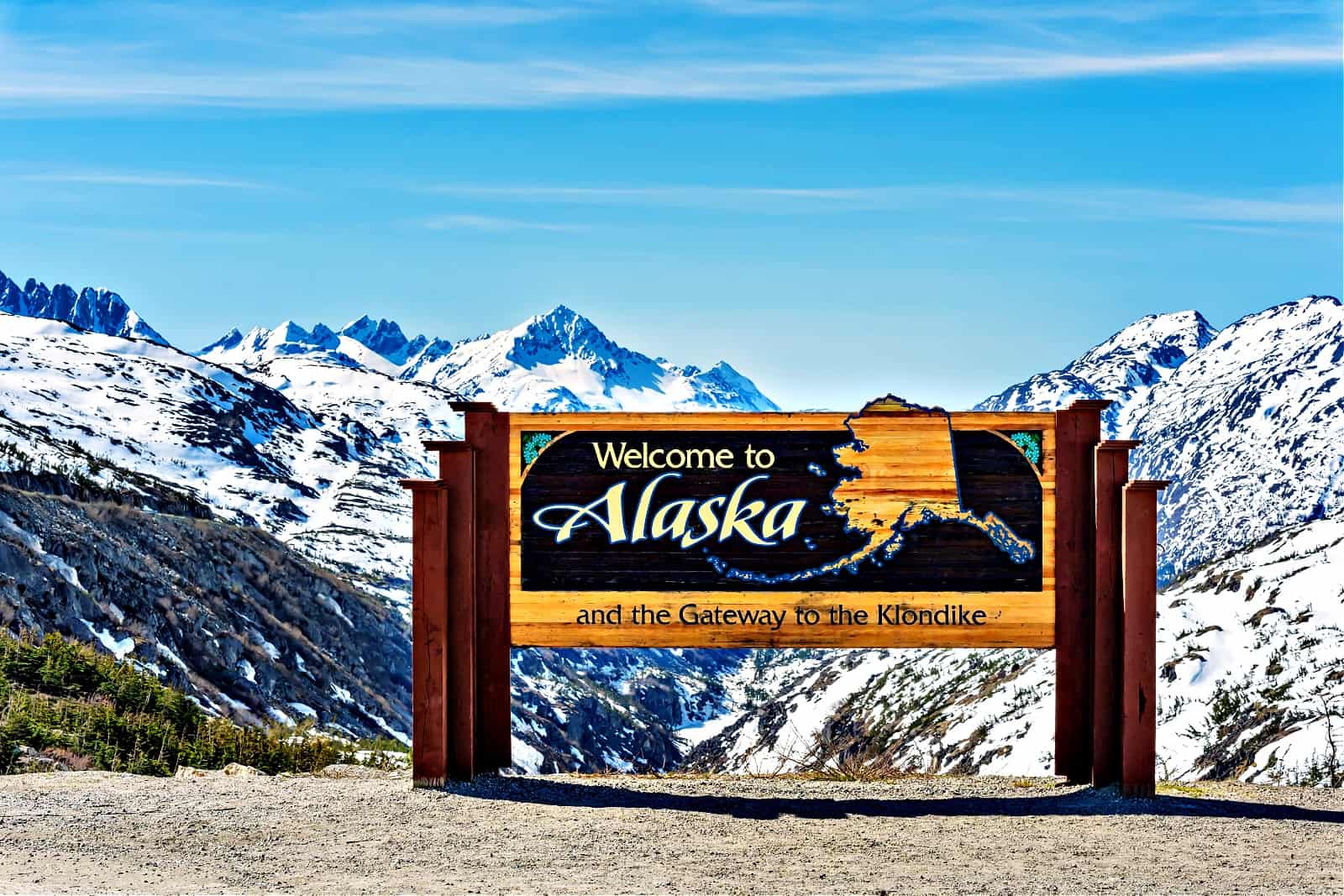 Alaska welcome sign with snow-capped mountains in the background
