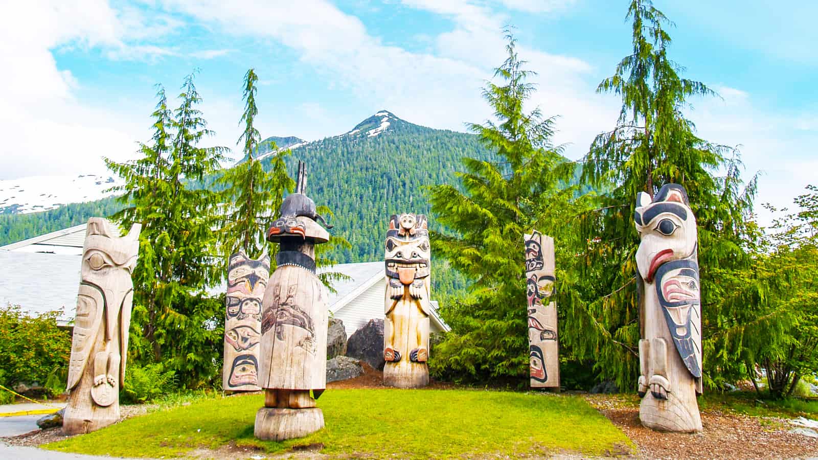 Circle of six American Indian totem poles against mountain background