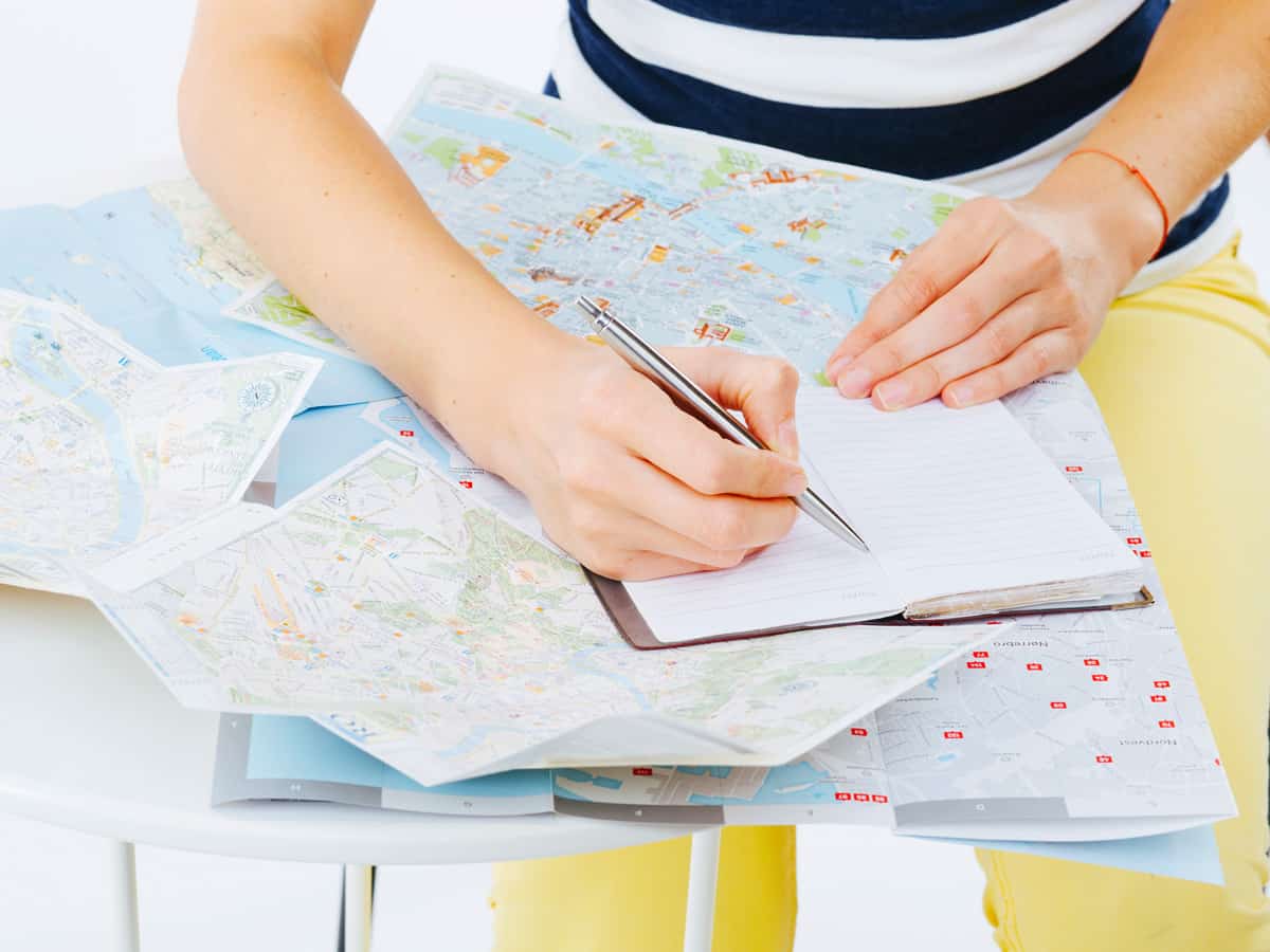 Planning a trip using maps and taking notes for the itinerary