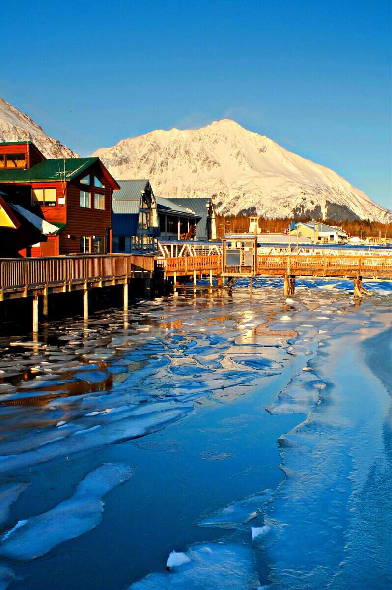 The ice is breaking up in the bay and marina below tall mountains in Seward Alaska