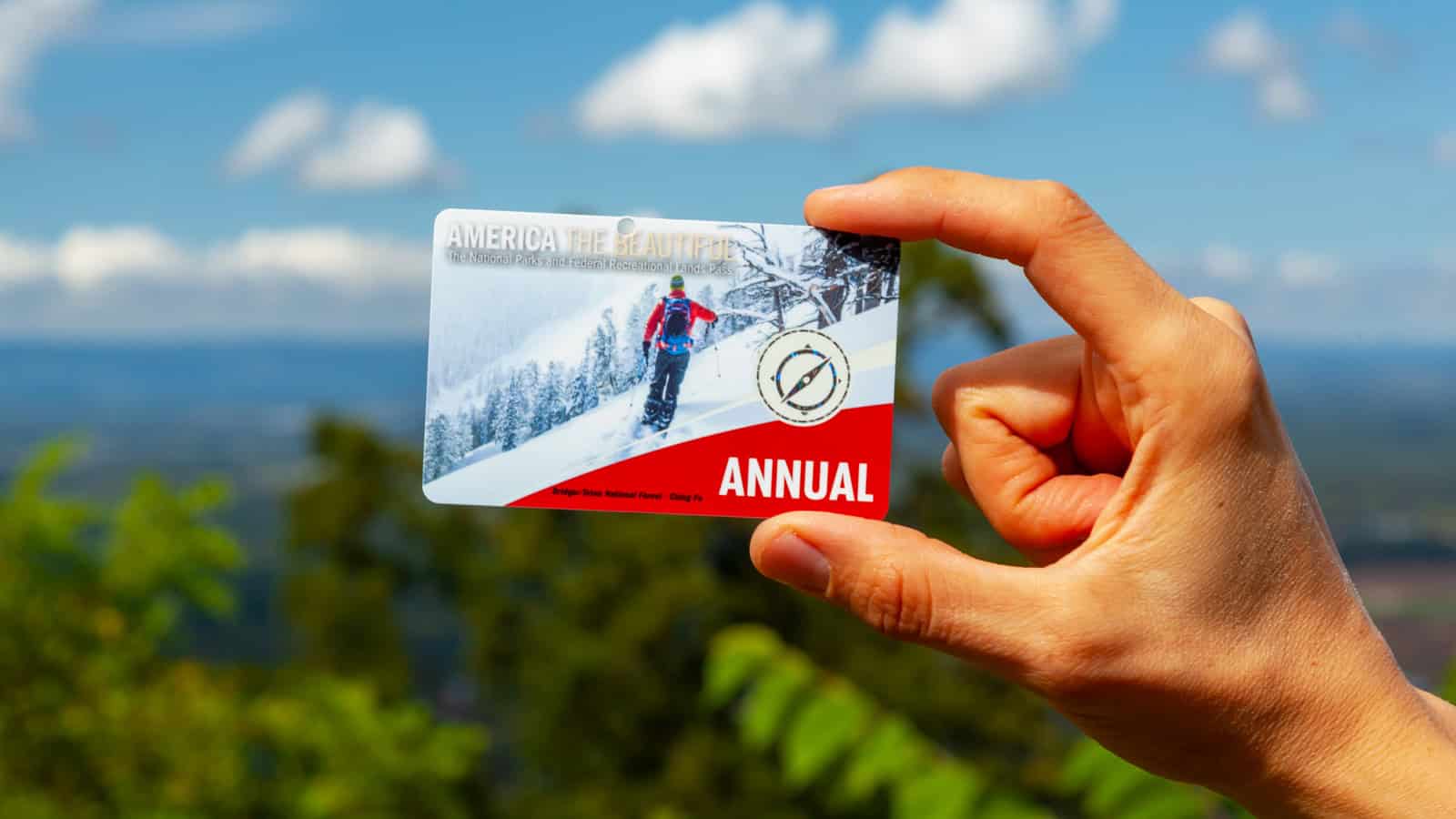 A woman is holding an 'America the beautiful' annual pass card against vista of Shenandoah