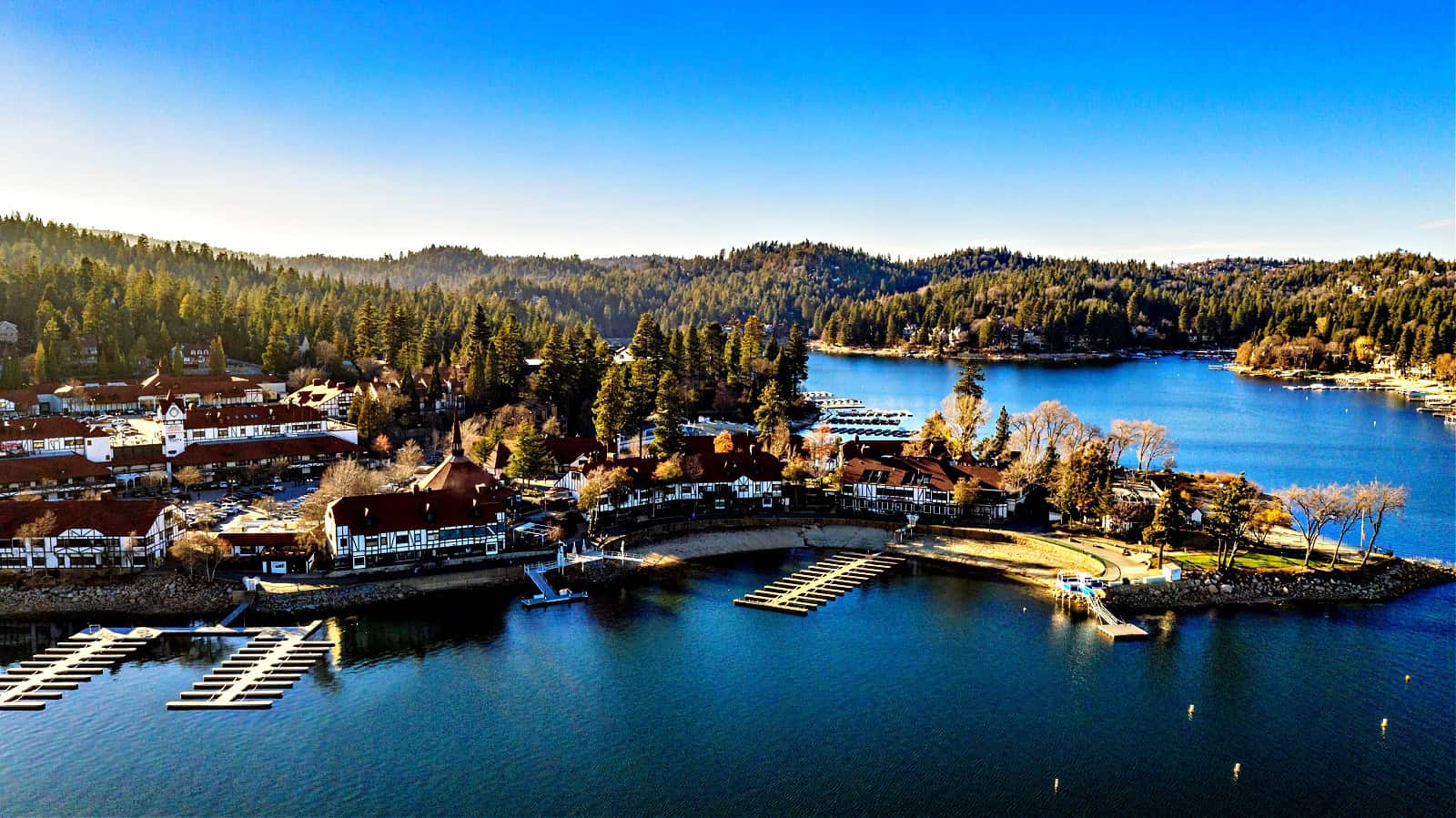 Aerial view of the Lake Arrowhead Village on Christmas Day, 2018, with beautiful snow, green trees, water reflections and clouds in the San Bernardino Mountains, California