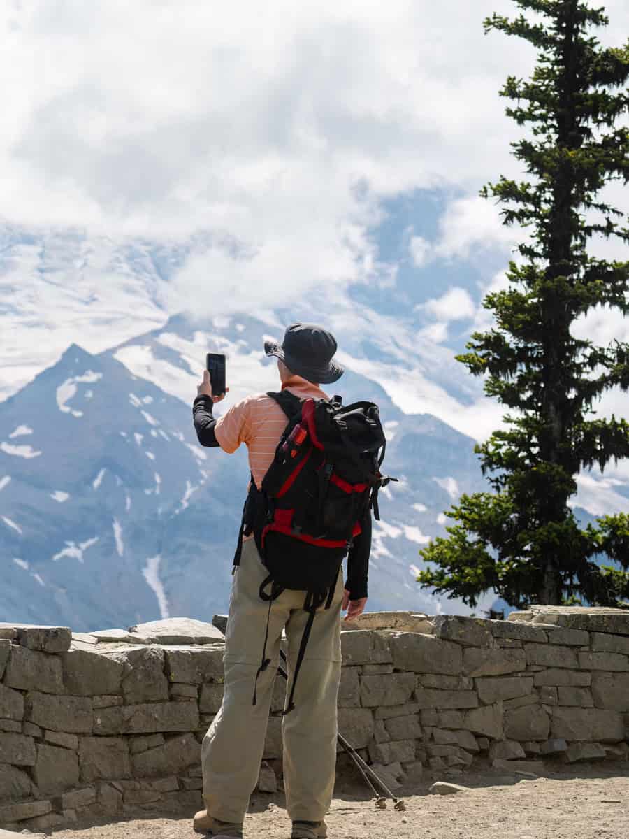 Backpacker taking photos of Glacier using a smartphone at Glacier Overlook