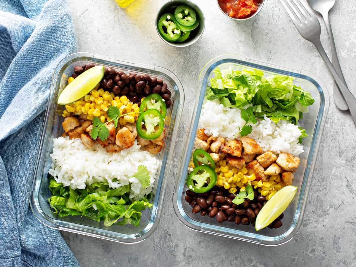 Healthy green mexican inspired meal prep with chicken, rice, beans, corn, salad