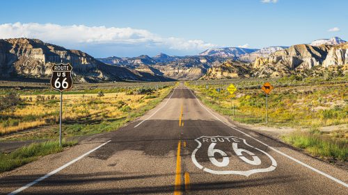 Scenic panoramic view of long straight road on famous Route 66 with historical street signs 1600x900
