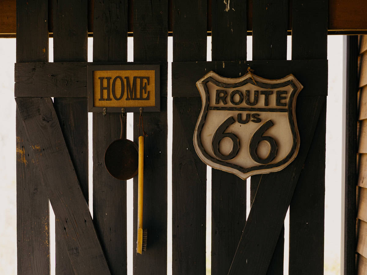 Vintage Route 66 Road Sign and Distressed Home Sign Hanging on Weathered Wooden Fence

