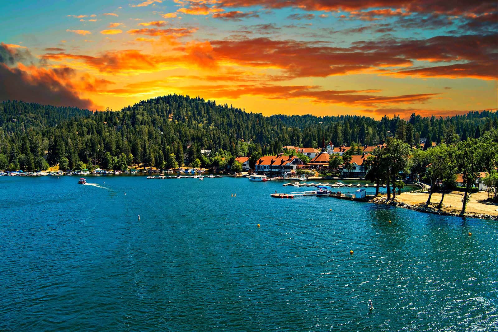 aerial shot of a gorgeous summer landscape at Lake Arrowhead with rippling blue water, boats sailing, boat docks and mountains covered in lush green trees in Lake Arrowhead California USA